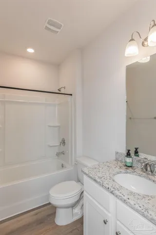 a bathroom with a granite countertop sink a toilet and bathtub