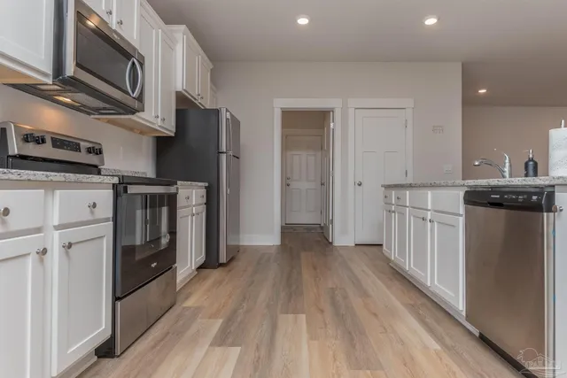 a kitchen with stainless steel appliances granite countertop a refrigerator a stove top oven a sink and dishwasher with wooden floor