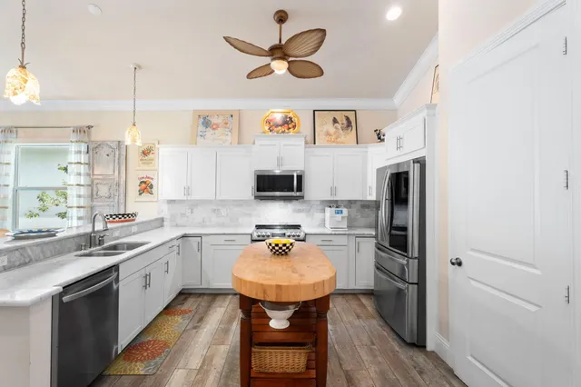 a kitchen with stainless steel appliances granite countertop a sink a stove a kitchen island with chairs and white cabinets