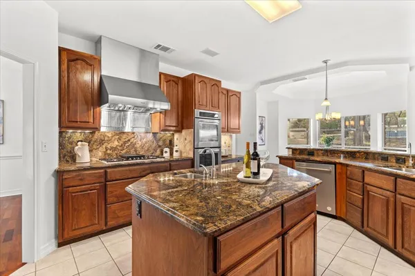 a kitchen with granite countertop kitchen island stainless steel appliances a sink stove and cabinets