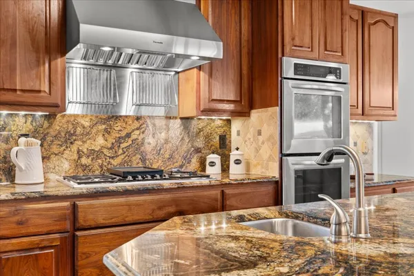 a kitchen with granite countertop a refrigerator and a stove top oven