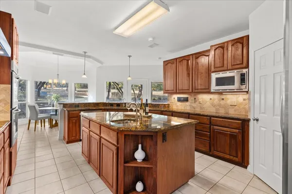 a kitchen with stainless steel appliances granite countertop a table chairs sink and cabinets
