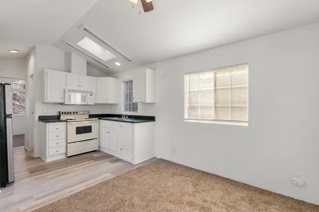 a kitchen with granite countertop white cabinets and white appliances