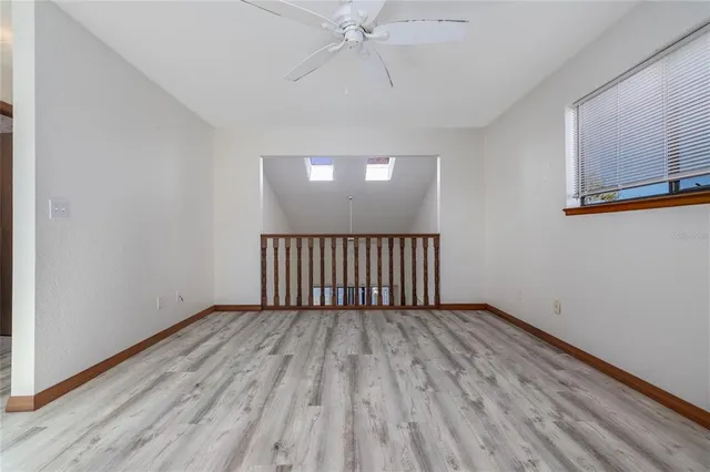 a view of a room with wooden floor fan and windows