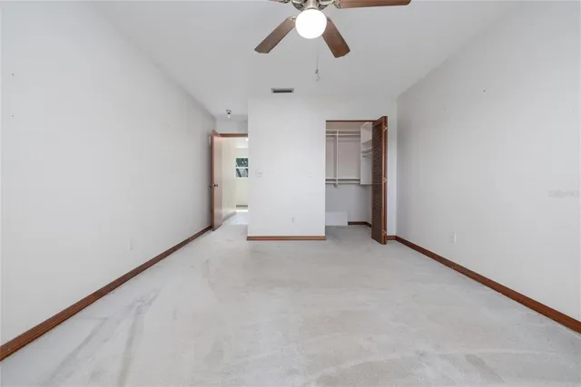 an empty room with chandelier fan and windows