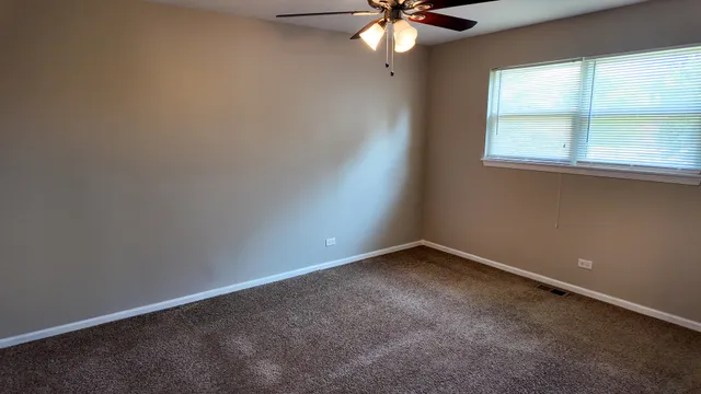 an empty room with closet and a chandelier fan
