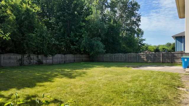 a view of a house with a yard plants and large tree