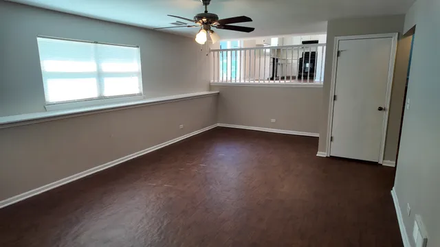 an empty room with a window and chandelier fan
