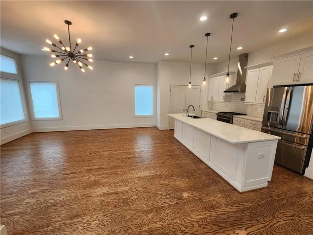 a large white kitchen with lots of counter space wooden floor and a ceiling fan