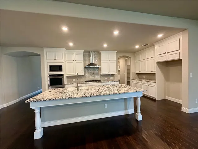 a kitchen with kitchen island a stove a refrigerator and a sink with wooden floor