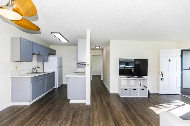 a kitchen with stainless steel appliances a stove top oven a sink a refrigerator white cabinets and wooden floor