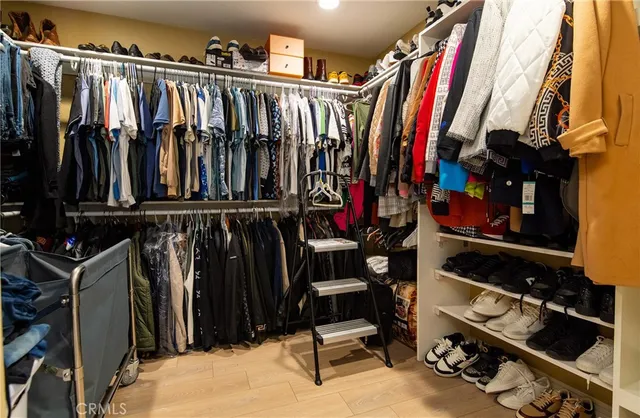 a view of walk in closet with clothes and shoes