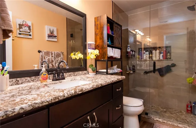 a bathroom with a granite countertop sink a toilet and a mirror