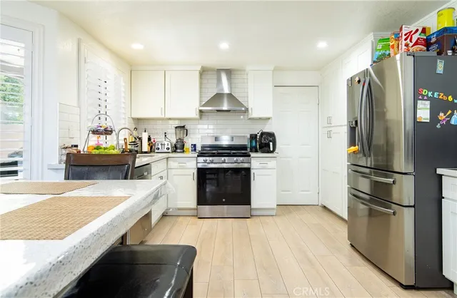 a kitchen with stainless steel appliances granite countertop a refrigerator a stove and a wooden floors