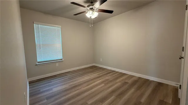 an empty room with a window and ceiling fan