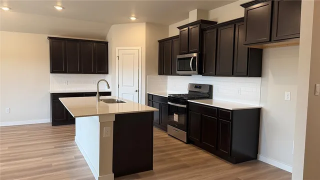 a kitchen with stainless steel appliances kitchen island granite countertop a sink stove and refrigerator