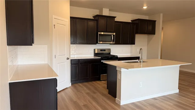 a kitchen with stainless steel appliances a stove a microwave a sink and cabinets
