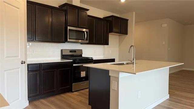 a kitchen with stainless steel appliances a sink a stove a microwave and wooden cabinets