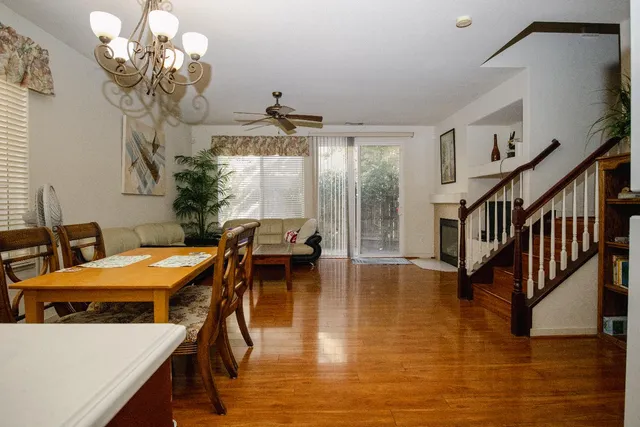 a dining room with wooden floor a chandelier a wooden table and chairs