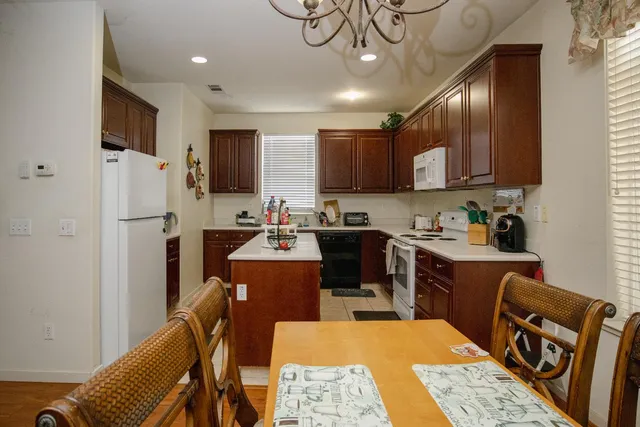 a kitchen with stainless steel appliances granite countertop a refrigerator a stove top oven a sink dishwasher and white cabinets with wooden floor