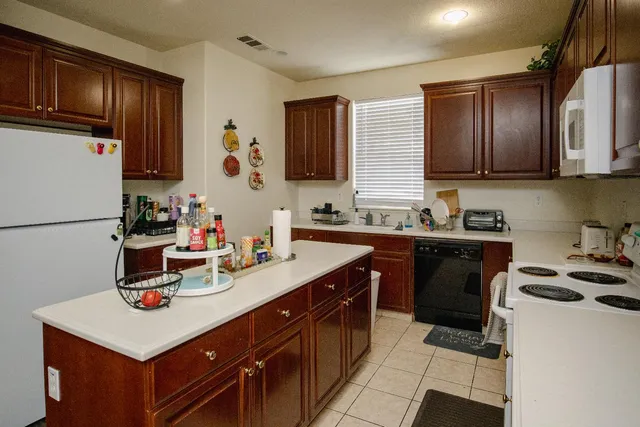 a kitchen with a sink dishwasher stove and refrigerator with wooden cabinet