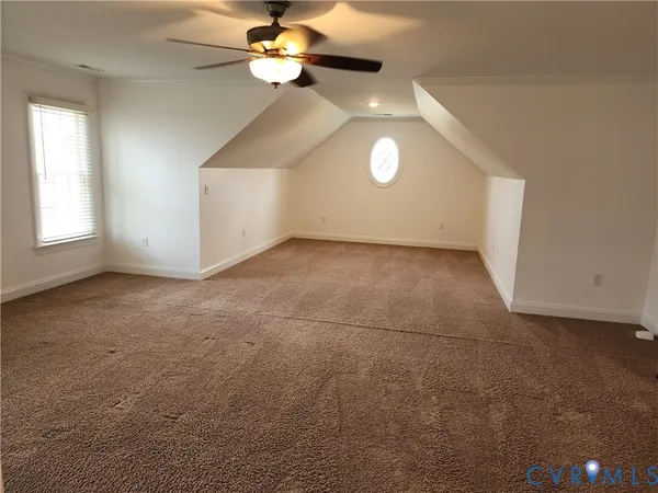 an empty room with a chandelier fan and windows