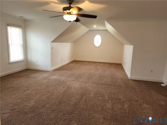 an empty room with a chandelier fan and windows