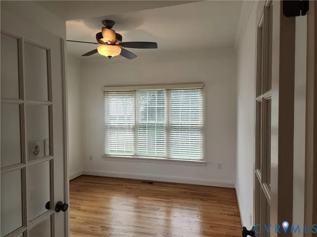 a view of an empty room with wooden floor and a window