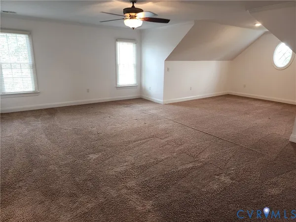 an empty room with a chandelier fan and windows