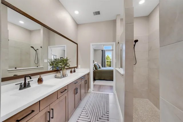 a en suite bathroom with a double vanity sink a mirror and a shower