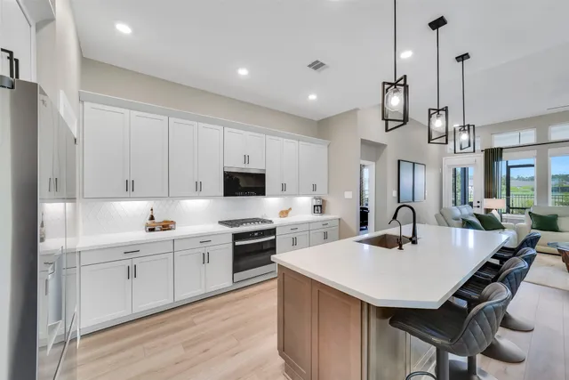 a kitchen with a sink a stove a refrigerator and white cabinets with wooden floor