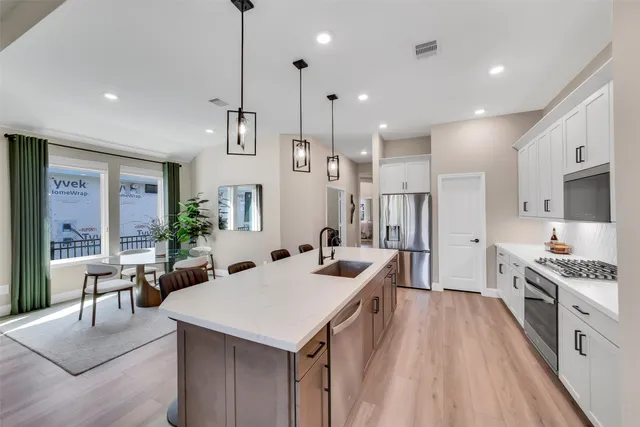 a kitchen with stainless steel appliances kitchen island granite countertop a sink and a refrigerator