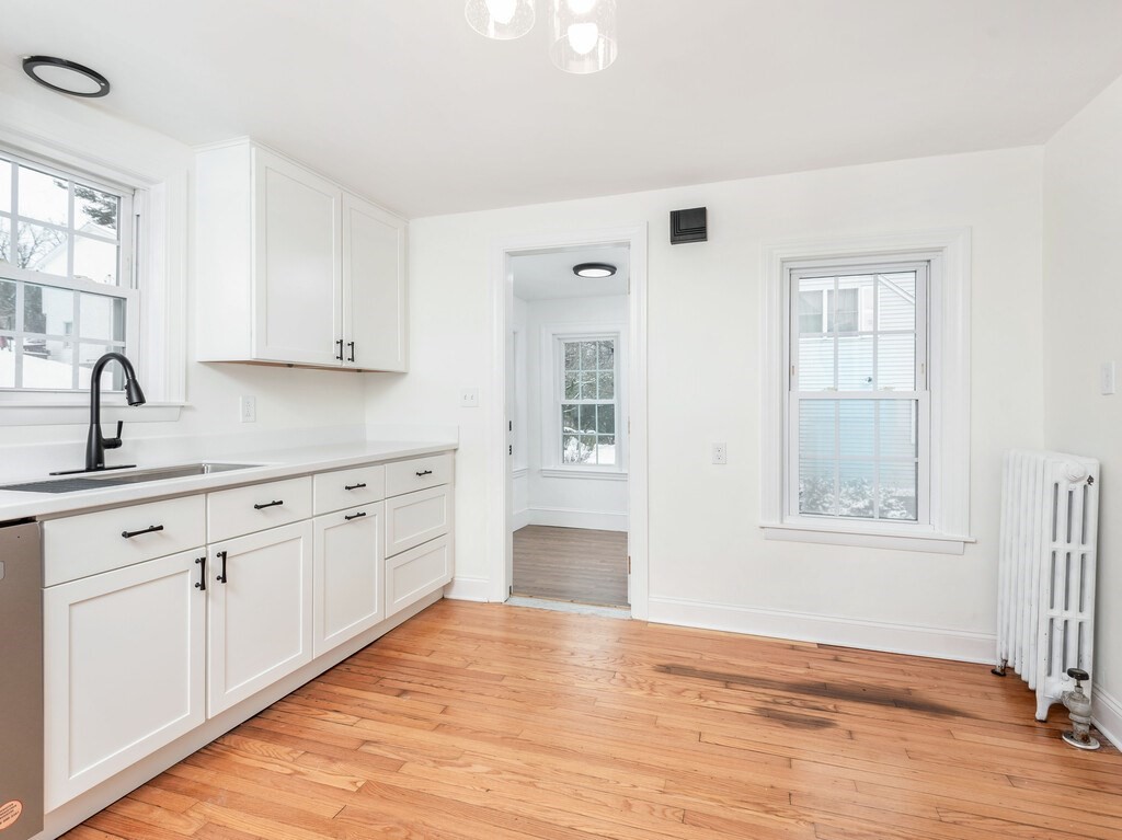 63 Upland Street Worcester, MA 01607 - Photo 8 of 36 a view of a kitchen with white cabinets and wooden floor