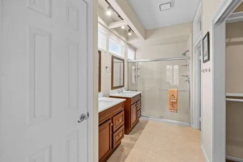 a bathroom with a double vanity sink a large mirror and a bathtub