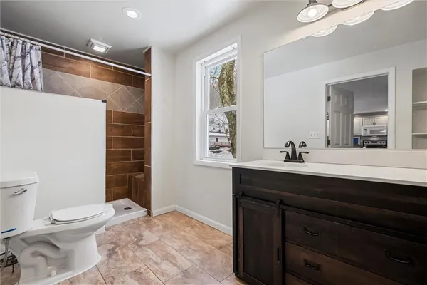 a bathroom with a sink a toilet a shower and a mirror