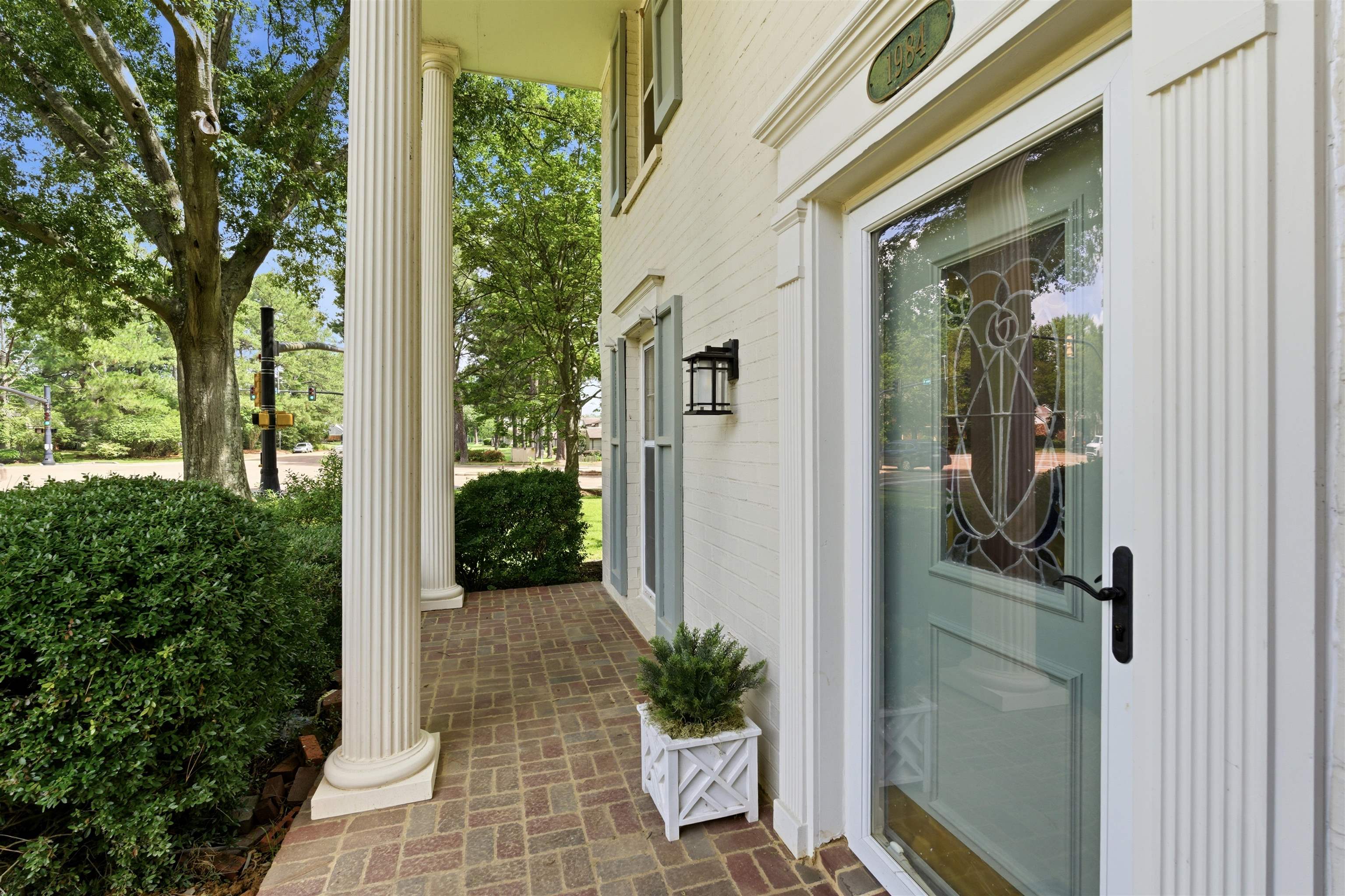 1984 Allenby Road Germantown, TN 38139 - Photo 7 of 37 Front porch featuring brick pavers, fluted columns, a decorative glass entry door, and exterior sconce lighting