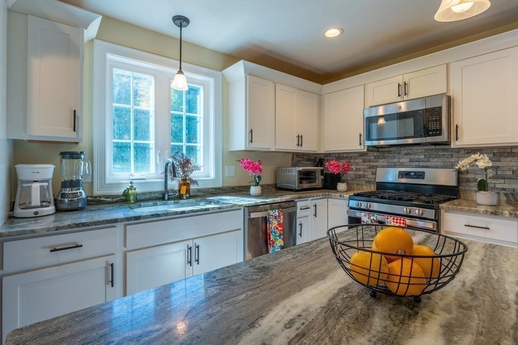 176 Oakham Road Barre, MA 01005 - Photo 22 of 36 a kitchen with stainless steel appliances granite countertop a stove a sink dishwasher a microwave oven and a dining table with wooden floor
