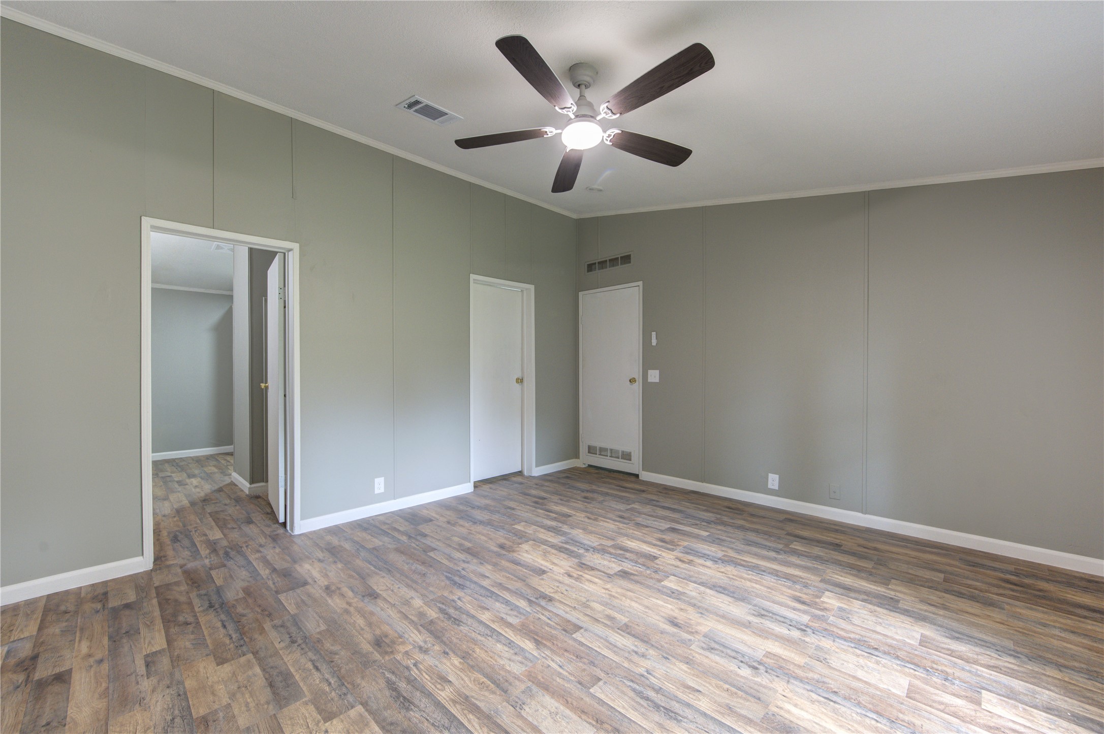30226 Davis Street Magnolia, TX 77355 - Photo 29 of 50 This room features light gray walls, wood-look flooring, a ceiling fan with lighting, and two doorways leading to adjacent spaces.