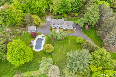 an aerial view of residential house with outdoor space and trees all around