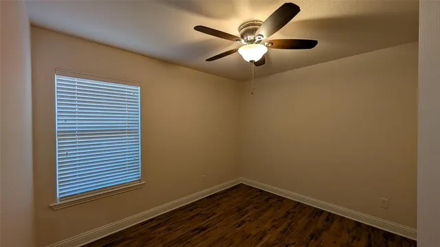 an empty room with wooden floor and a ceiling fan