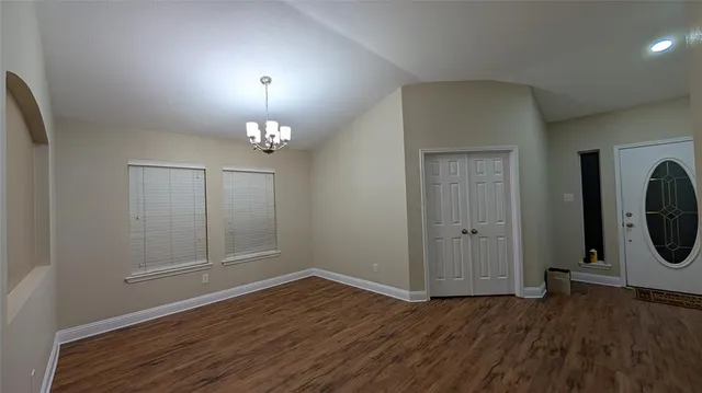 a view of a hallway with wooden floor and a chandelier