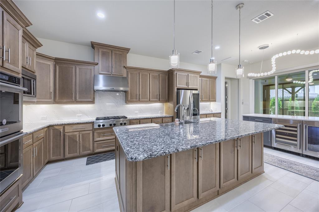 918 Sydney Lane Allen, TX 75013 - Photo 8 of 40 The kitchen features extensive cabinetry, a large kitchen island with a granite countertop, and stainless steel appliances including a built-in oven, microwave, and refrigerator