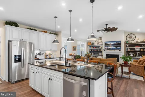a kitchen with stainless steel appliances granite countertop a refrigerator sink and white cabinets