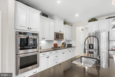 a kitchen with stainless steel appliances a refrigerator sink and white cabinets