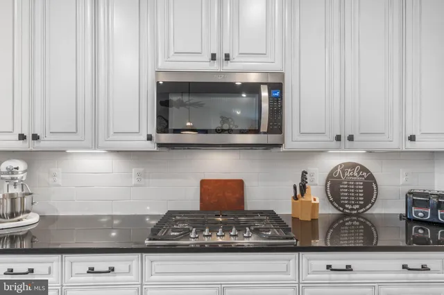 a kitchen with granite countertop a sink a counter top space appliances and a view of living room