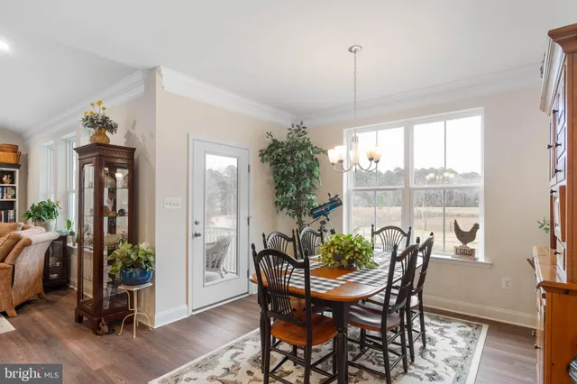 a kitchen with stainless steel appliances kitchen island granite countertop a stove a refrigerator a sink a dining table and chairs with wooden floor