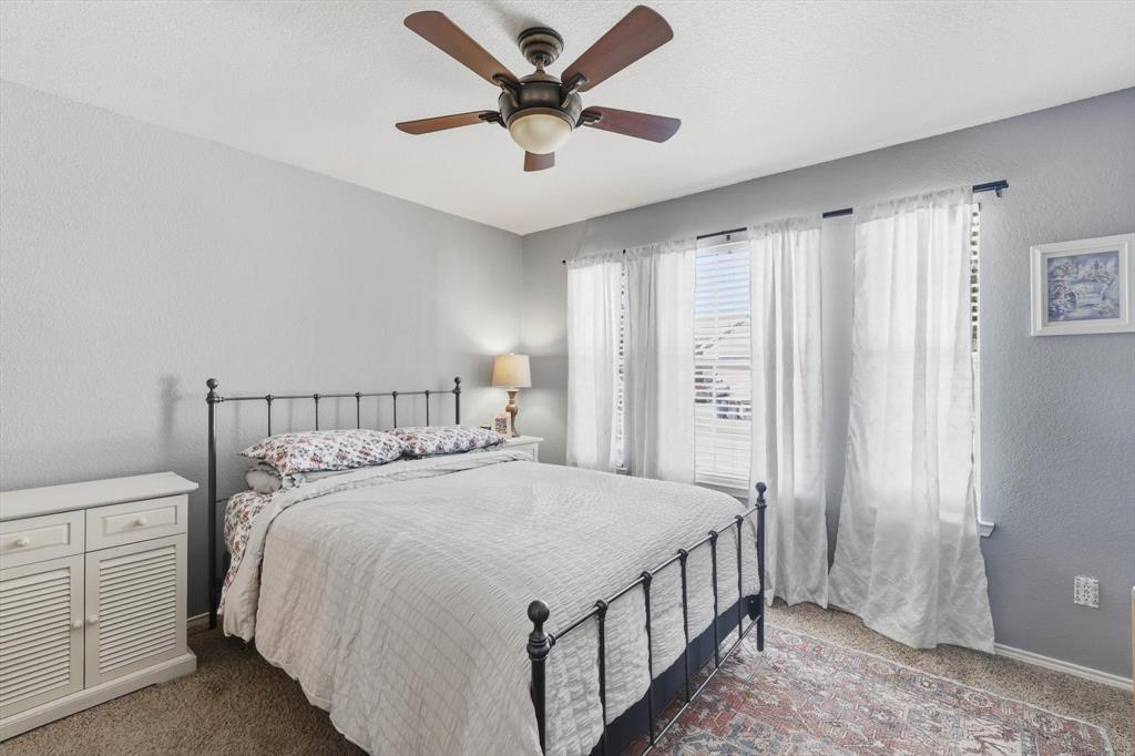 1201 Roping Reins Way Fort Worth, TX 76052 - Photo 28 of 34 a bedroom with a large bed and a chandelier