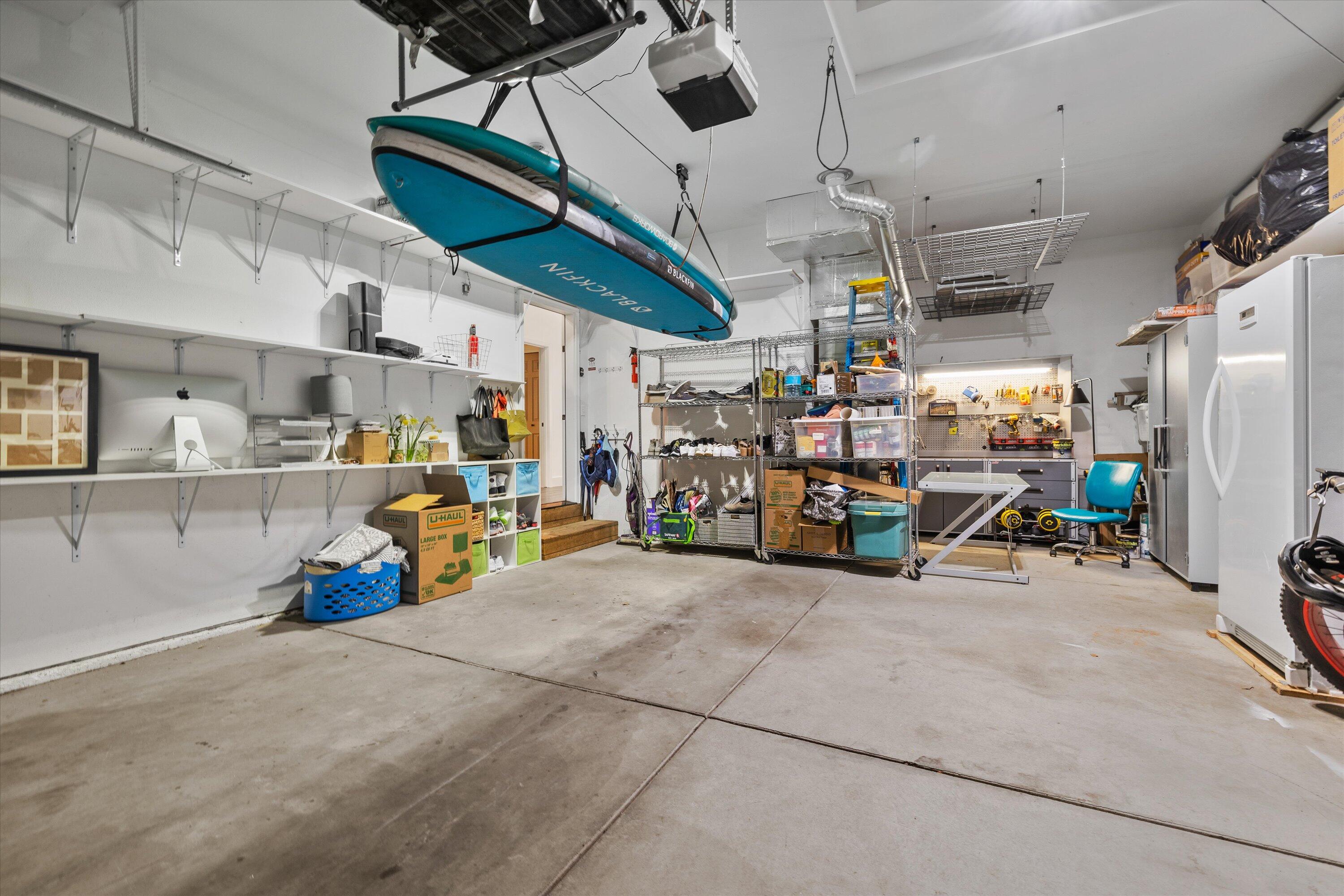 61269 Southwest Brookside Loop Bend, OR 97702 - Photo 38 of 46 Two car garage outfitted with a Tesla charger, workbench and cabinets, as well as many shelves, hanging space for paddle board/kayaks and bikes