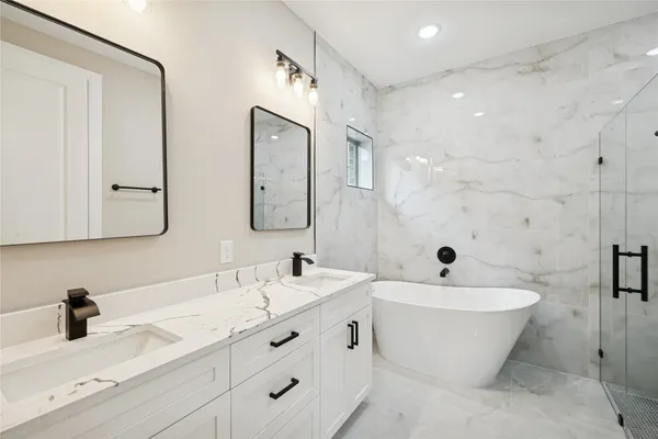 a bathroom with a double vanity sink mirror and bathtub