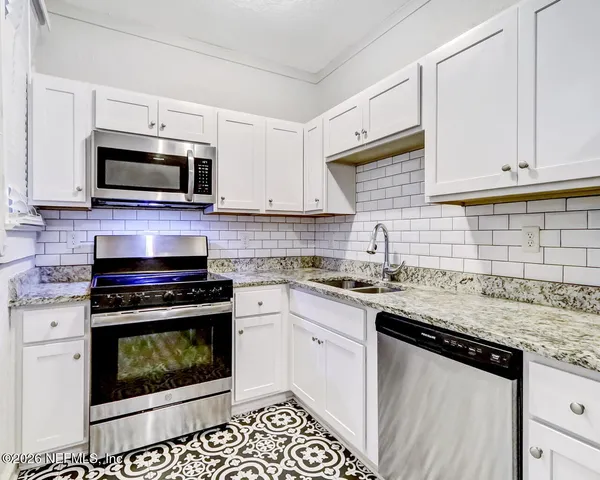 a kitchen with granite countertop a stove sink microwave and cabinets